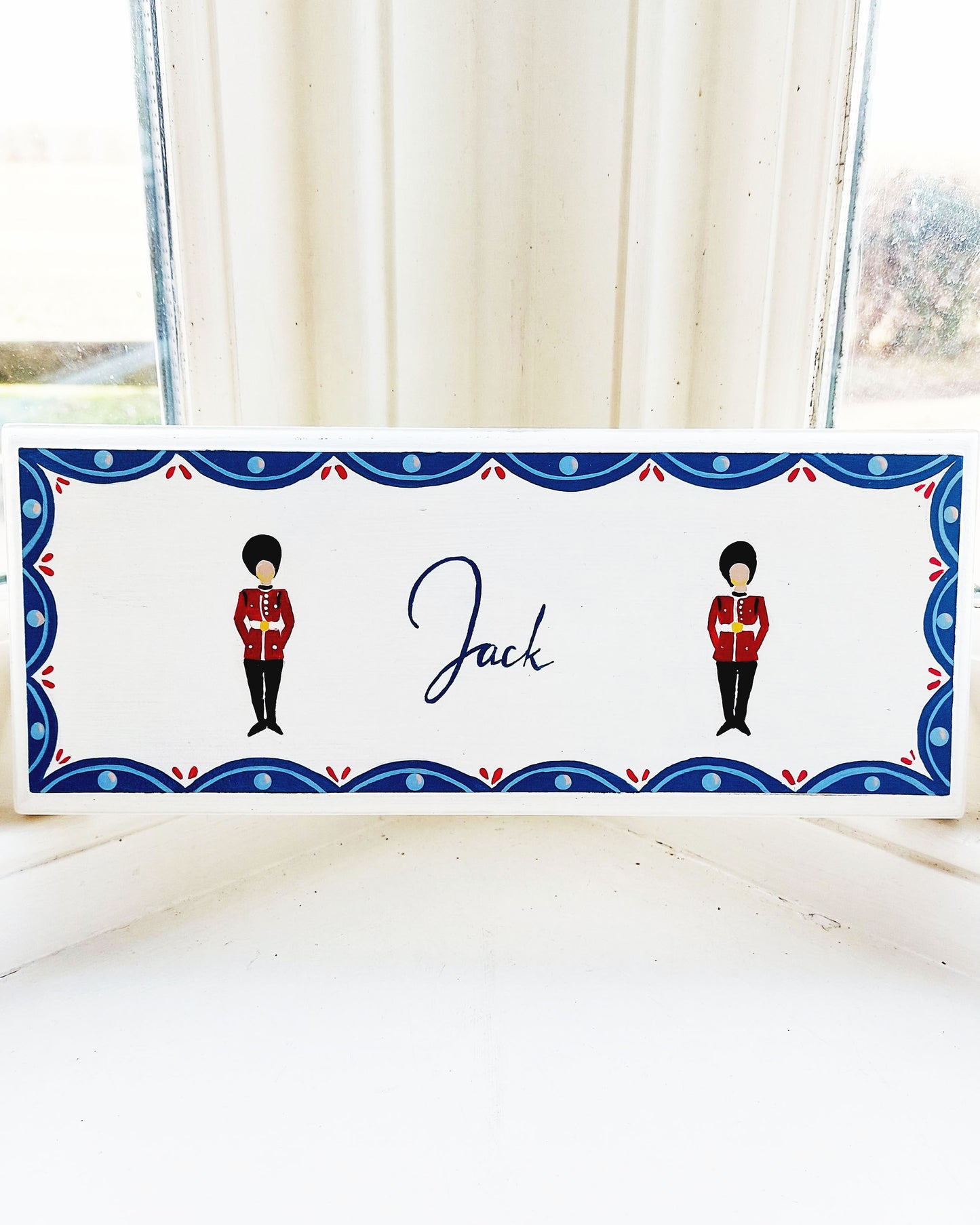 Nursery door sign personalised with the name 'Jack', featuring striking grenadier guards aand a decorative blue scalloped border, perfect for baby room decor.