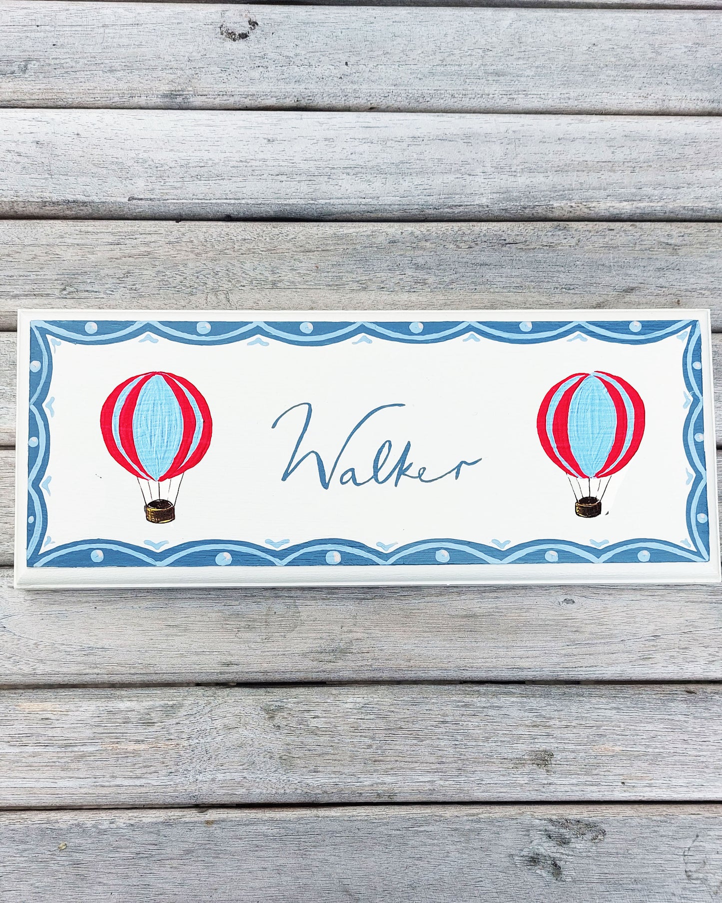 Nursery door sign personalised with the name 'Walker', featuring whimsical red and blue hot air balloons and a decorative blue scalloped border, perfect for baby room decor.