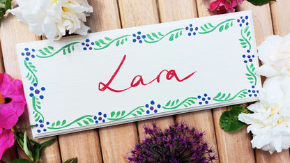 Nursery door sign personalised with the name 'Lara', featuring striking grenadier guards and a decorative blue and green floral border, perfect for baby room decor.