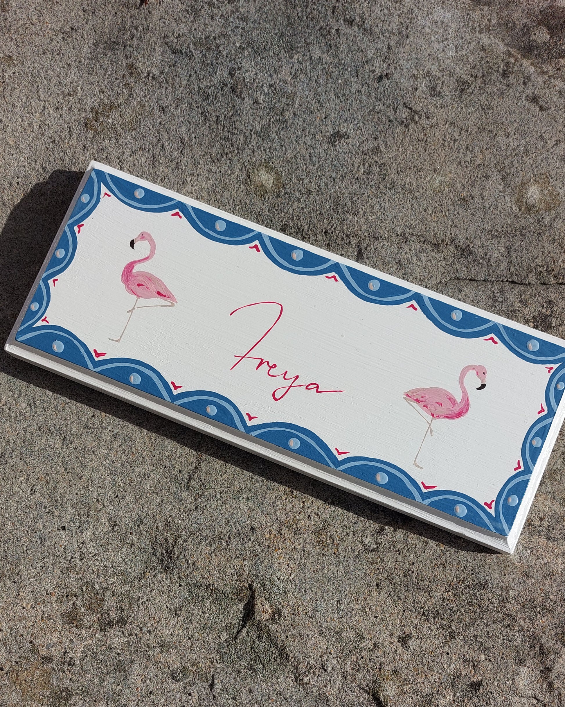 Nursery door sign personalised with the name 'Freya', featuring majestic flamingoes and a decorative blue scalloped border, perfect for baby room decor.