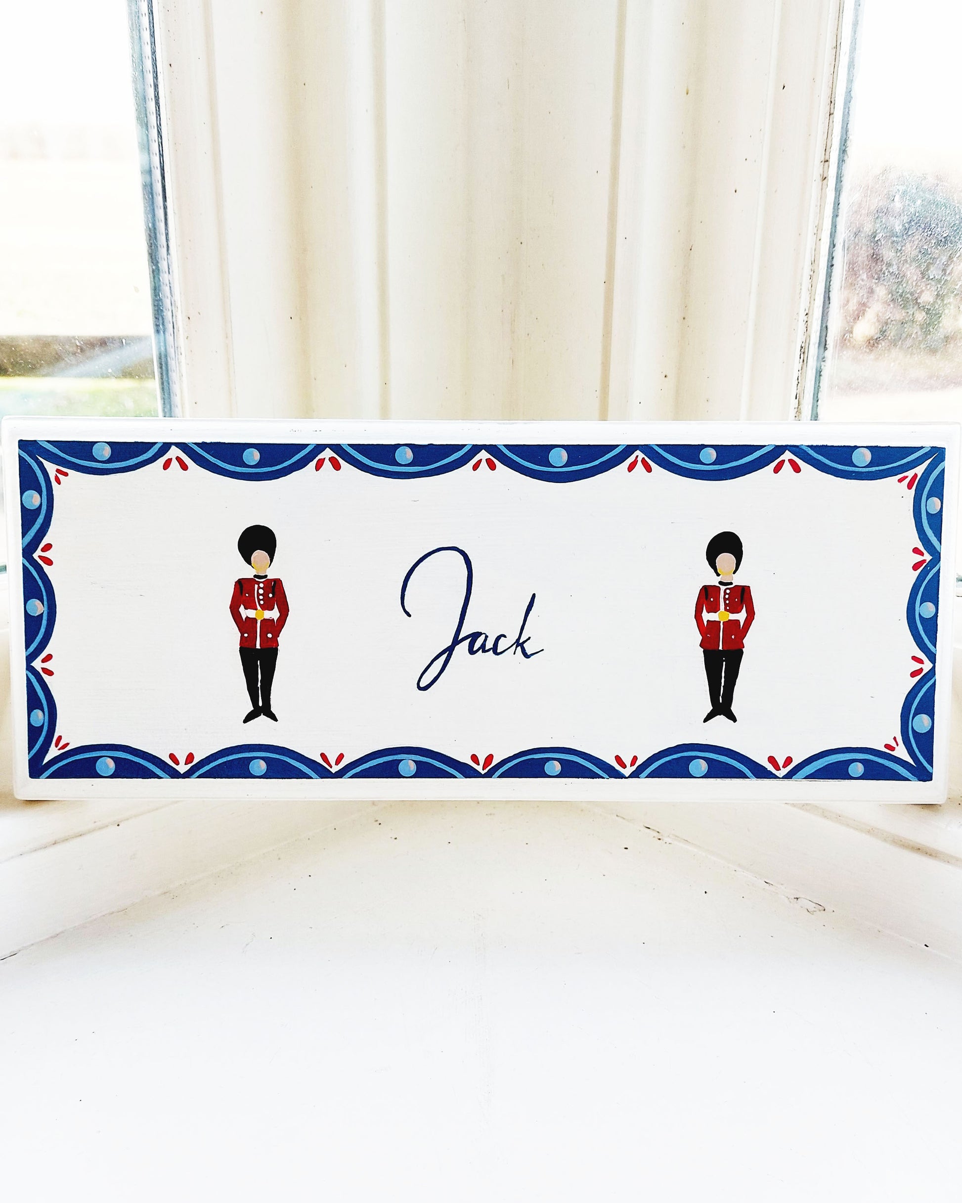 Nursery door sign personalised with the name 'Jack', featuring striking grenadier guards aand a decorative blue scalloped border, perfect for baby room decor.