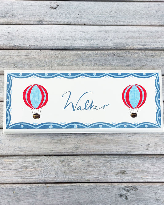 Nursery door sign personalised with the name 'Walker', featuring whimsical red and blue hot air balloons and a decorative blue scalloped border, perfect for baby room decor.