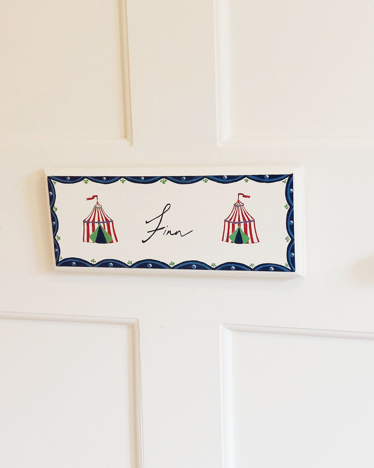 Nursery door sign personalised with the name 'Finn', featuring Circus big tops and a decorative blue scallop border, perfect for baby room decor.