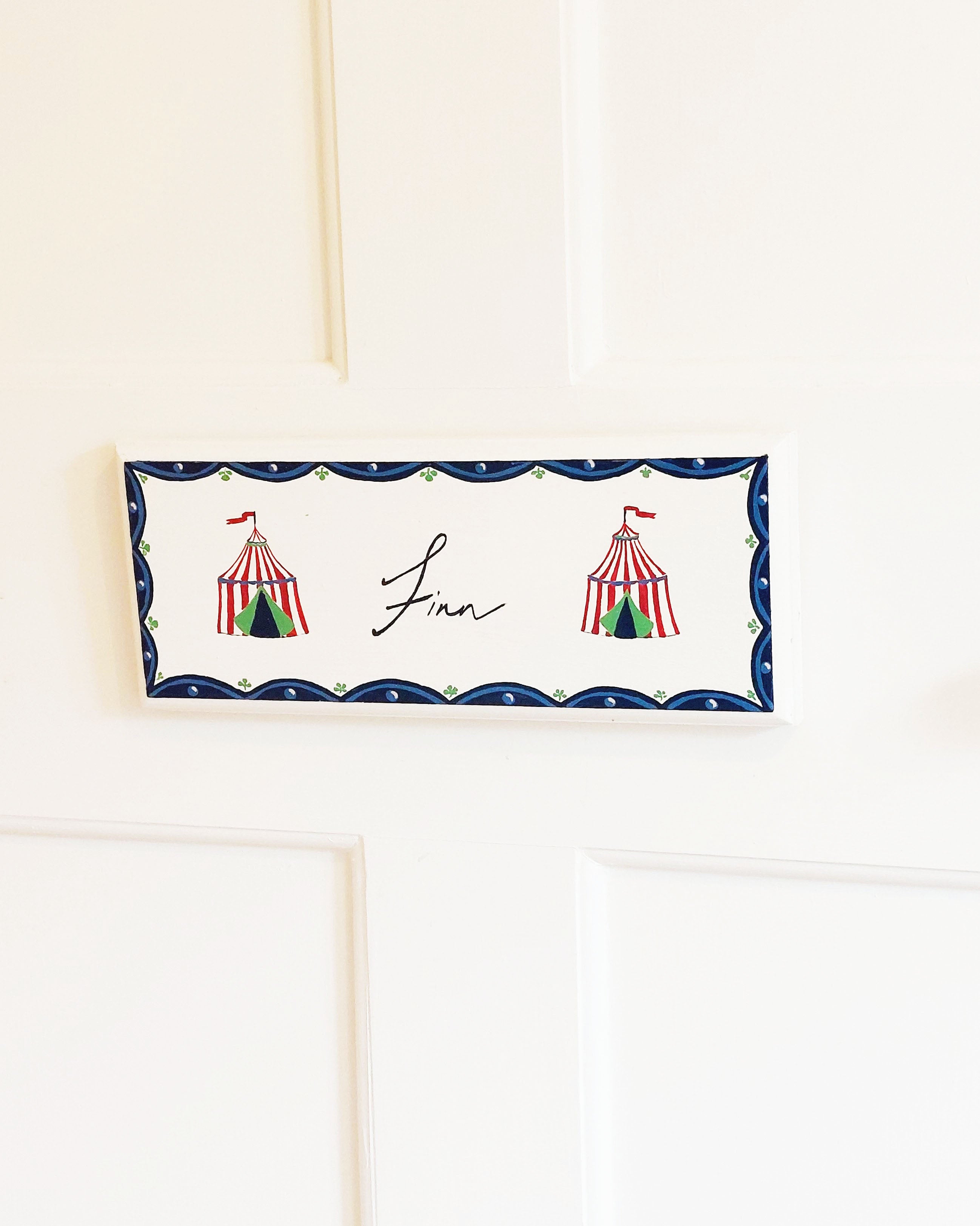 A hand-painted nursery door sign featuring the circus and the name 'Finn'.