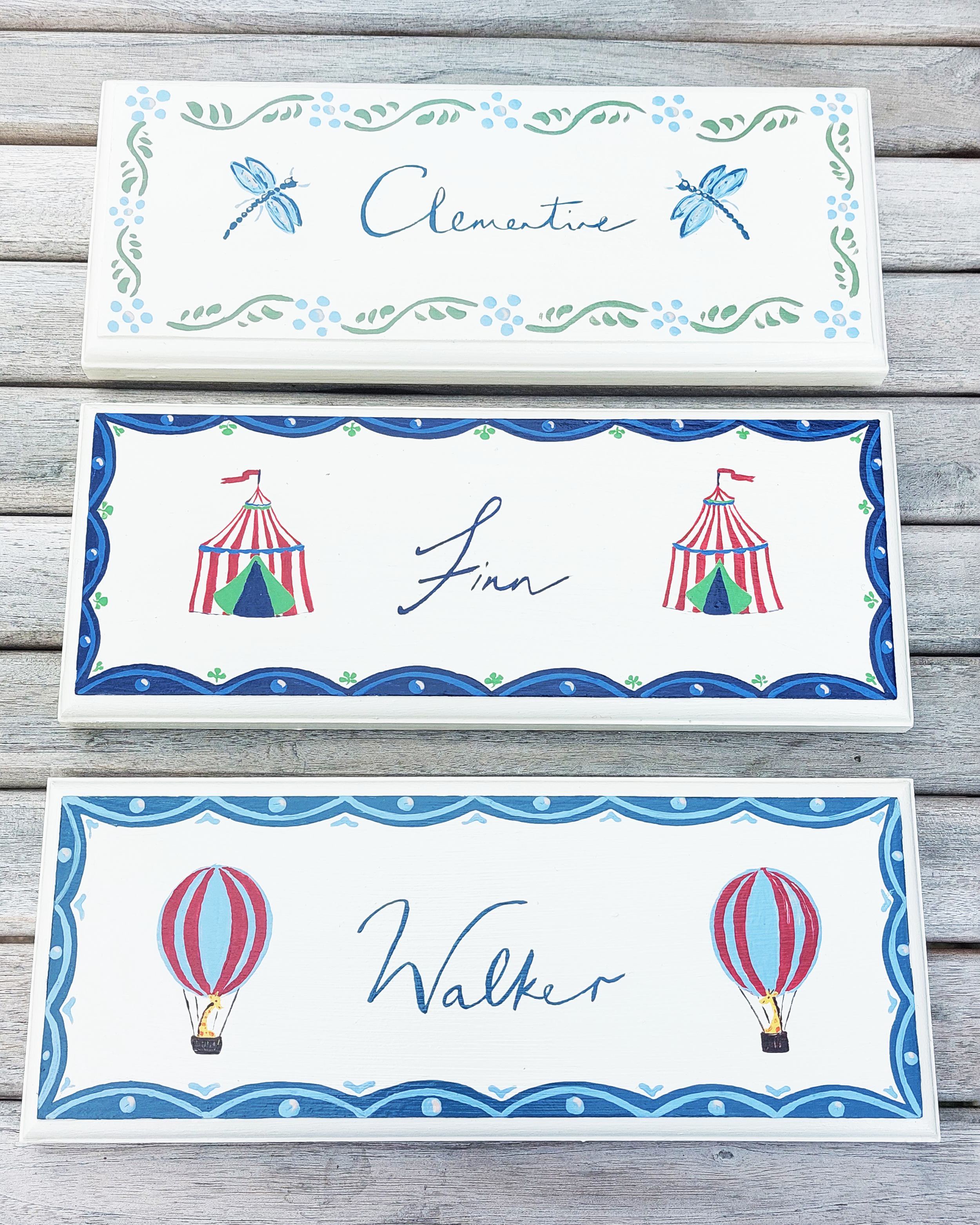 A collection of hand-painted nursery door signs features unique names and designs. 